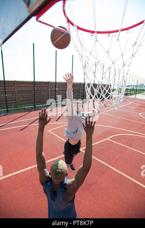 Portrait de deux jeunes hommes jouant au basket-ball et le saut par hoop en cour de plein air, copy space Banque D'Images