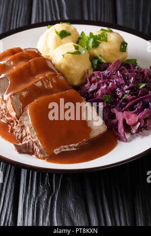 Le plat traditionnel Sauerbraten avec boulettes de pommes de terre et chou rouge gros plan sur une assiette. Vertical la cuisine allemande. Banque D'Images