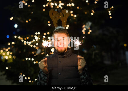 Les gens, les vacances de Noël - concept et surpris l'homme dans les cornes de cerf tenant deux baguettes à la lumière ou à l'extérieur des bengals Banque D'Images