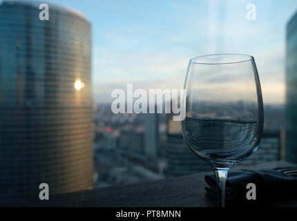 Verre sur table avec aerial cityscape au coucher du soleil sur l'arrière-plan. Concept de loisirs de luxe. L'accent peu profondes Banque D'Images