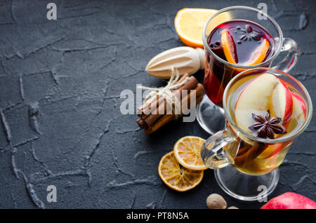 Deux verres de différents type de vin chaud ou de gluhwein basé sur les vins rouge et blanc avec des épices et ingrédients sur fond noir. Chaud épicé bever Banque D'Images