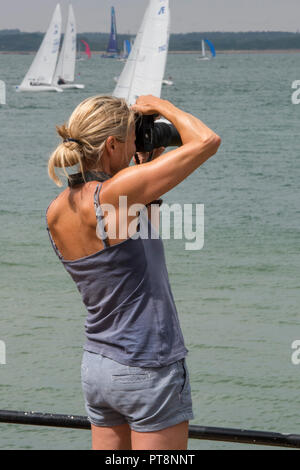 Une jeune femme aux cheveux blonds photographier le yacht racing à Cowes Week régate sur l'île de Wight. Dame photographe de sport avec appareil photo. Banque D'Images