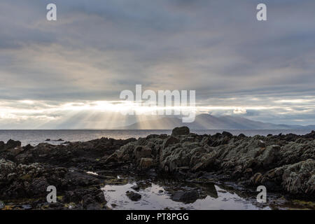 Rayons crépusculaires sur les montagnes de Mourne et de la mer d'Irlande et piscine dans les rochers en premier plan vu de St John's Point, comté de Down, Irlande du Nord. Banque D'Images