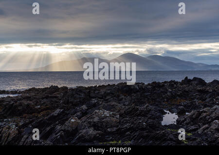 Rayons crépusculaires sur les montagnes de Mourne et rive rocheuse de St John's Point, comté de Down, Irlande du Nord. Banque D'Images