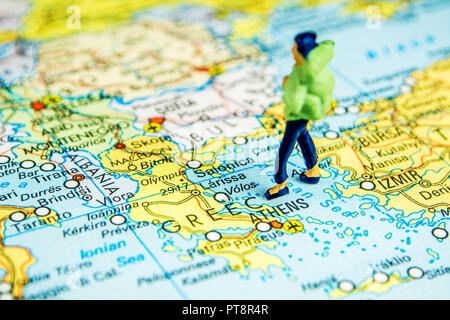 Libre de figurine miniature de jeune voyageur debout sur une grande carte Grèce Banque D'Images