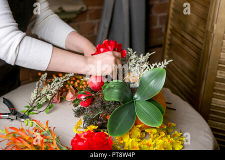 Un fleuriste au travail : Comment faire une pièce maîtresse de l'action de grâce avec grande citrouille et bouquet de fleurs. Pas à pas, tutoriel. Banque D'Images