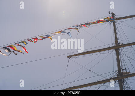 Nautique voile coloré drapeaux au vent des lignes d'un mât de voilier rétroéclairé lumineux ciel bleu par le ciel nuageux jour de tempête. Tons rétro Banque D'Images