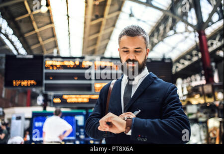 L'homme d'affaires sur la station de train à Londres, contrôle du temps. Banque D'Images