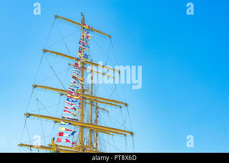 Nautique voile coloré drapeaux au vent des lignes d'un mât voilier dans Ciel bleu rétro-éclairé par le soleil. Banque D'Images