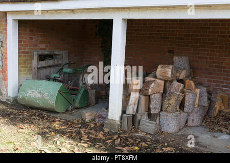 Outhouse (dépendance, bâtiment) utilisés pour le stockage des logs et une vieille tondeuse (tondeuse) Banque D'Images