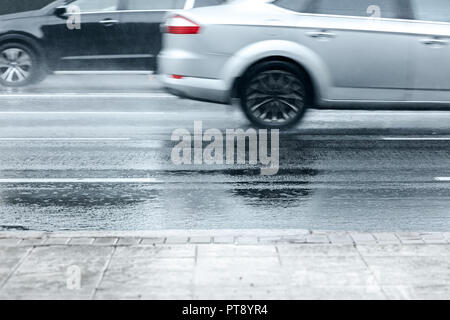 Ville inondée route asphaltée avec wagons en mouvement à vitesse élevée lors de fortes pluies Banque D'Images