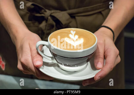 Portrait of a female barista servant avec ses mains une juste fait un cappuccino. Banque D'Images