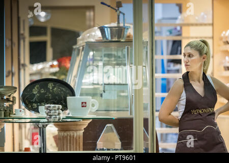 Pylos, Grèce - Octobre 2th, 2018 : une femme travaillant dans une boulangerie - pâtisserie est debout à l'entrée à l'extérieur à l'écart à la commercial cen Banque D'Images