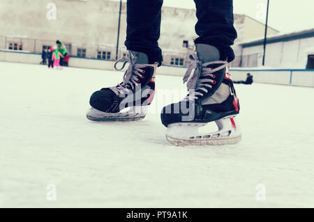 Pieds sur les patins d'une personne roulant sur la patinoire sur le fond de la patinoire en plein air. vieux sports patins. sur une jambe de l'homme. pl Banque D'Images