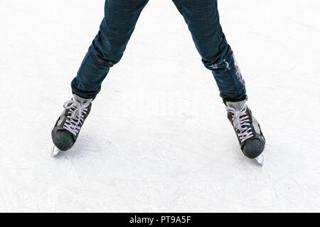 Patins à glace en mouvement Vue de dessus Gros plan sur la glace blanche. Jambes en jeans noir sur les patins. Le sport amateur. Loisirs d'hiver Banque D'Images