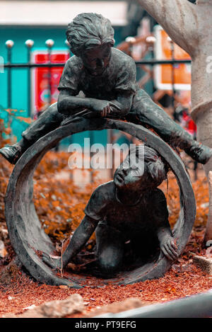 Statue de deux petits garçons jouant dans un tube près d'une clôture au Royaume-Uni Banque D'Images