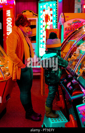 Femme et un enfant qui joue dans une attraction sur une machine à sous penny au Royaume-Uni Banque D'Images