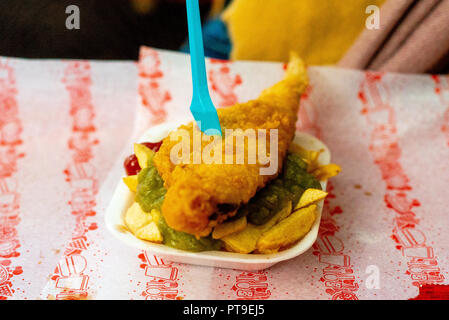 De savoureux à pêcher sur les petits pois et frites dans un carton sur papier rouge et blanc avec une fourchette bleue mangée à Matlock UK Banque D'Images