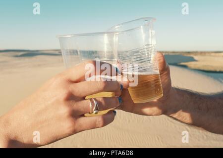 Santa Cruz, Bolivie - 5 septembre 2018 : jeune femme et l'homme clinking verres en plastique de bière dans le désert Banque D'Images