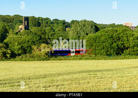 Leeds, Angleterre, Royaume-Uni - 30 juin 2015 : une Classe 333 Northern Rail train passager électrique sur la ligne passe Airedale les ruines de Kirkstall Abbey, partie Banque D'Images