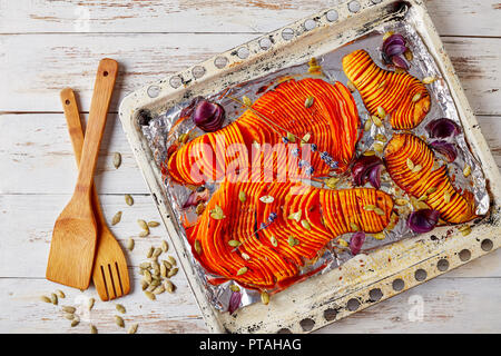 Tranches de citrouille cuite au four sur une plaque à pâtisserie rustique avec oignon, épices et lavande séchées, vue de dessus, télévision lay Banque D'Images