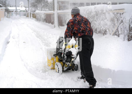 La souffleuse d'exploitation de l'homme d'enlever la neige sur l'allée. Un homme d'une zone de nettoyage à l'aide d'un chasse-neige à essence. Un homme nettoie la neige des trottoirs à snowbl Banque D'Images