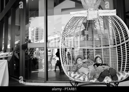 Des enfants assis et se prélasser dans un grand fauteuil d'ananas, goupilles marché sur Flinders Street, Central Business District de la ville de Townsville QLD, Australie Banque D'Images