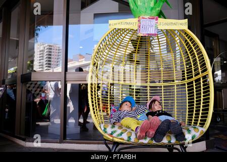 Des enfants assis et se prélasser dans un grand fauteuil d'ananas, goupilles marché sur Flinders Street, Central Business District de la ville de Townsville QLD, Australie Banque D'Images