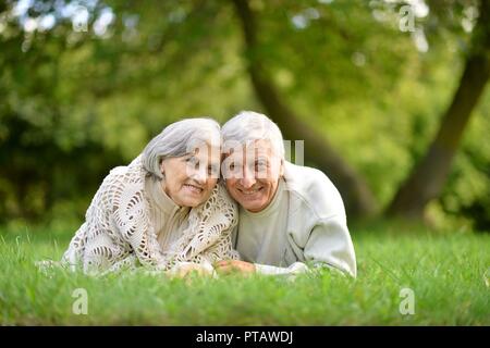 Portrait of elderly couple allongé sur l'herbe verte en été park Banque D'Images