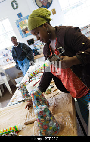 Une femme du fait de vases de vieille bouteille tops pour faire de l'argent dans le canton village d'Imizamo Yethu un bidonville à Hout Bay, Cape Town, South Afri Banque D'Images