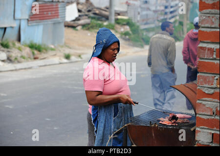 Un résident d'une cuisson steak sur un grill ouvert dans le canton village d'Imizamo Yethu un bidonville à Hout Bay, Cape Town, Afrique du Sud 2008 Banque D'Images