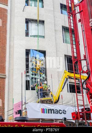 Entrepreneur en construction Mace les travailleurs sur une grue de levage montage soigneusement une grande nouvelle vitre dans un bâtiment à Mayfair, Londres, UK Banque D'Images
