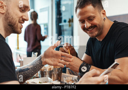 Deux amis de manger des hamburgers. frites, s'amusant et en souriant d'un café. Banque D'Images
