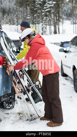 Senior couple gardant un ski board et bâton de ski près de voiture Banque D'Images