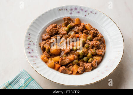 La sapt traditionnel turc kebab avec des pommes de terre, pois et tomate dans une assiette blanche. Ragoût de viande juteux organique. Banque D'Images