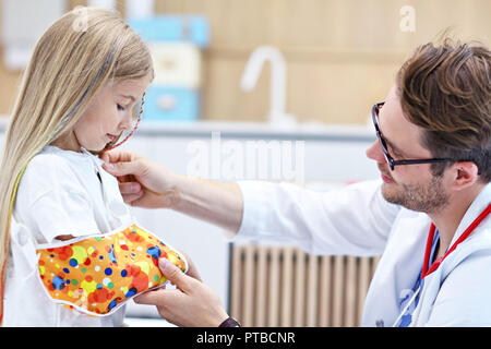 Photo de l'homme contrôle de pansement pédiatre little girl's bras cassé Banque D'Images