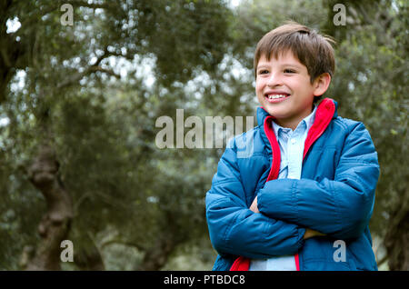 Portrait of a cute boy debout avec les bras croisés, souriant, regardant la caméra Banque D'Images