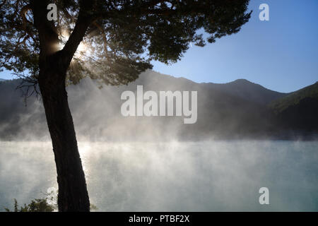 Brume du matin se lève sur le lac de Castillon dans la vallée du Verdon Alpes de Haute Provence France Banque D'Images