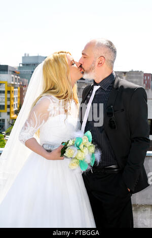 Concept de mariage. L'heureux couple de mariage beau sont debout et s'embrasser sur le toit de l'immeuble. Le marié et la mariée dans l'amour. Banque D'Images