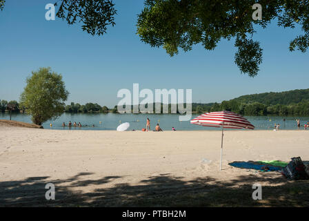 Le Lac des Varennes à Marcon, Pays de la Loire, avec la natation et le canoë-kayak. Soleil, ciel bleu avec du sable doré et des parasols colorés. Banque D'Images