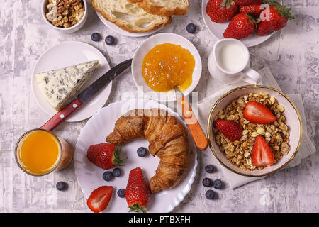 Petit-déjeuner sain:avec du lait, granola, fraise, fromage, confiture jus pain croissant sur fond blanc télévision lay Banque D'Images