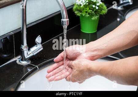 Le lavage des mains au robinet Chrome sur le lavabo dans la salle de bains moderne Banque D'Images