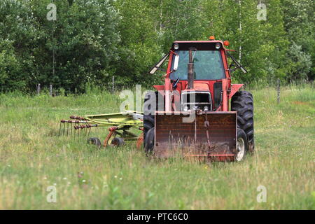 Québec,Canada. Tracteur agricole avec hay rake stationné dans la zone Banque D'Images