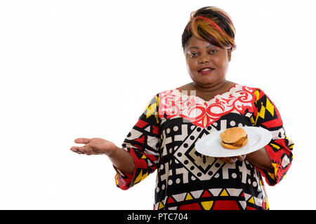 Studio shot of happy fat black African woman smiling while showi Banque D'Images