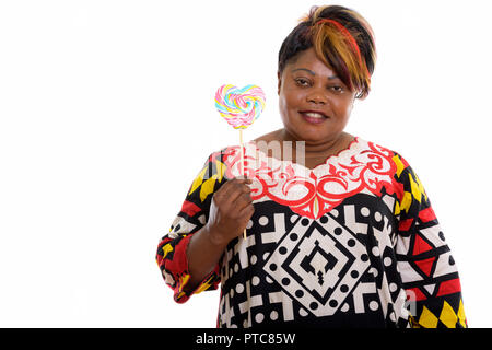 Studio shot of happy fat black African woman smiling while holdi Banque D'Images