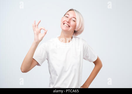 Young adult woman court avec les cheveux colorés montrant ok signe. Banque D'Images