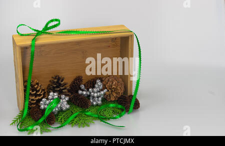 Cônes de pin et de l'argent mini-billes sur un lit de branches de cèdre à l'intérieur d'une boîte d'ombre avec un ruban vert il d'encadrement Banque D'Images