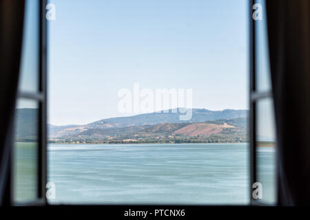 Le Lac Trasimène à Castiglione del Lago, Ombrie, Italie vue paysage à partir de la fenêtre ouverte dans l'hôtel par beau jour d'été, l'eau turquoise bleu Banque D'Images