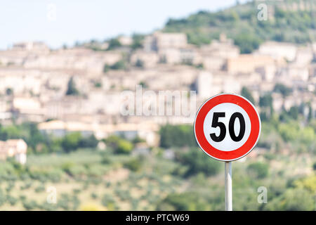 La limite de vitesse de 50 kilomètres par heure km signe avec l'arrière-plan flou de la ville ou village ville d'Assise en Ombrie, Italie paysage urbain au cours de l'été ensoleillé Banque D'Images