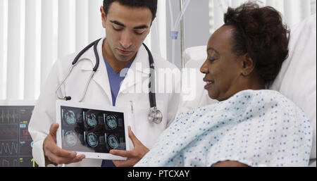 Portrait of Hispanic médecin montrant ct-scans sur tablet au patient Banque D'Images
